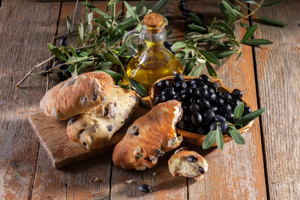 traditional italian puccia bread with black olives cutting board with olive oil fresh olive
